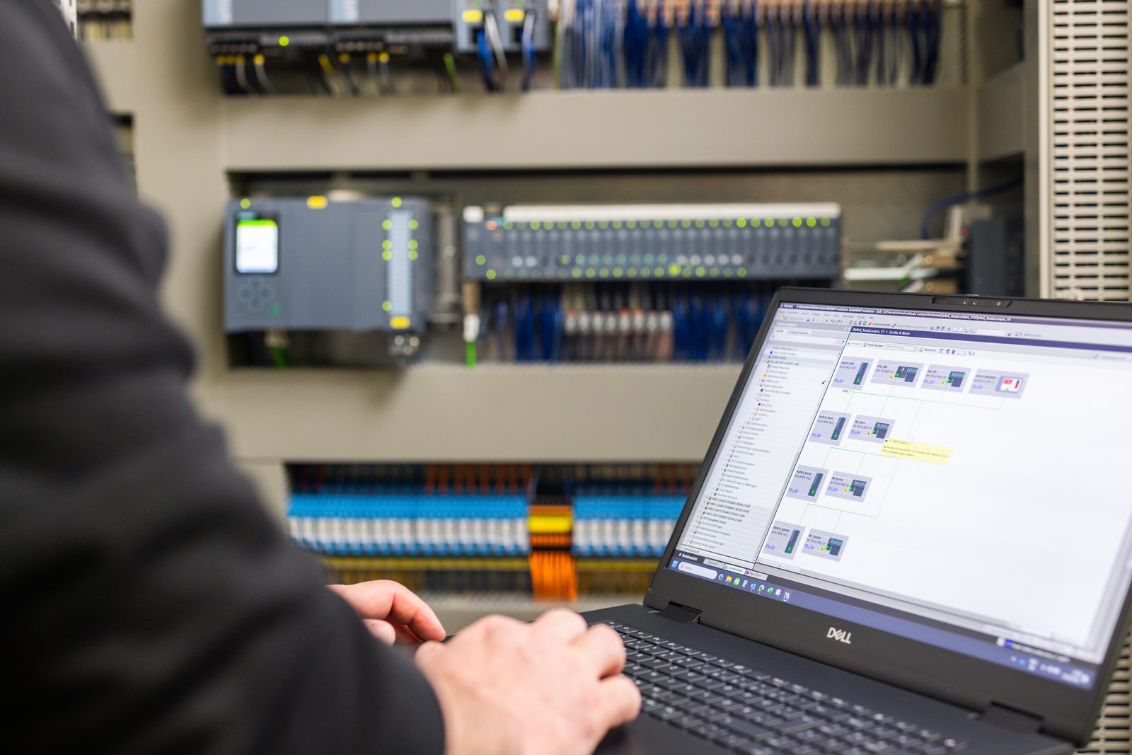 A person programming a controller in a control panel on a laptop