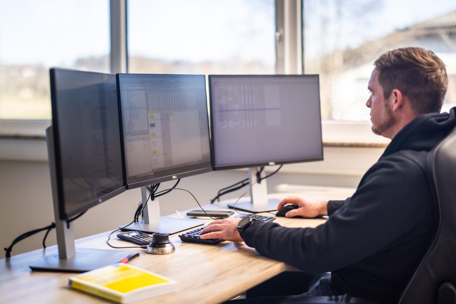 A person working at a computer with three screens