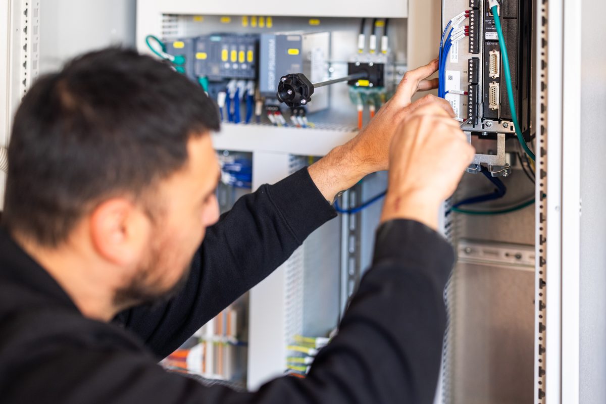 Person wiring components on a mounting plate