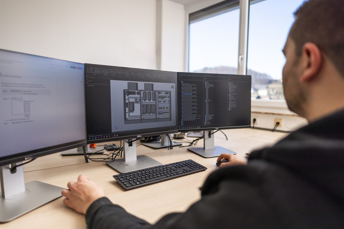Employee designing a control panel in 3D on three screens